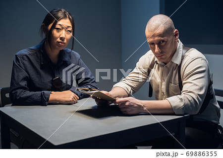 An experienced police officer and his young assistant sit at the table and sort out the case An experienced police officer and his young assistant sit at the table and sort out the case 69886355