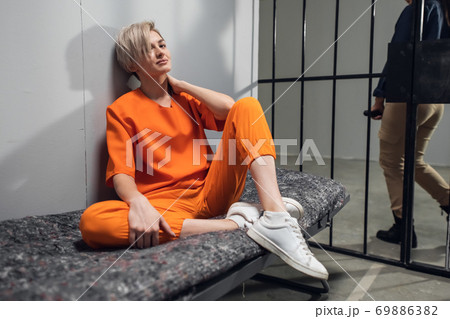 Sad criminal girl in her cell on a bed worries about her fate 69886382