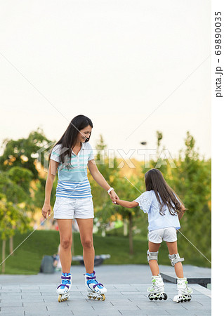 Young mother and her little daughter rollerskating 69890035