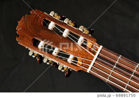 Closeup of acoustic guitar frets, fretboard, tuners, headstock and truss rod 69891750
