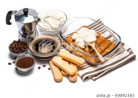 tiramisu dessert cooking - Traditional Italian Savoiardi ladyfingers Biscuits and cream in glass baking dish isolated on white with clipping path 69892383