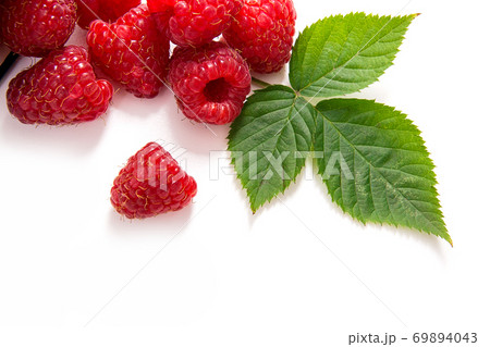 White cup with ripe raspberries and green leaf isolated on white background. White cup with ripe raspberries and green leaf isolated on white background. 69894043