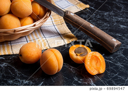 Fresh organic apricots in basket. Group of harvested apricots in basket with vintage knife.. 69894547
