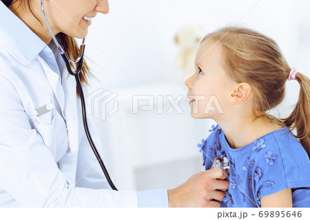 Doctor examining a little girl by stethoscope. Happy smiling child patient at usual medical inspection. Medicine and healthcare concepts 69895646