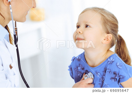 Doctor examining a little girl by stethoscope. Happy smiling child patient at usual medical inspection. Medicine and healthcare concepts Doctor examining a little girl by stethoscope. Happy smiling child patient at usual medical inspection. Medicine and healthcare concepts 69895647