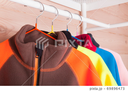 Colorful fleece jackets are hanging on hangers, close-up 69896473