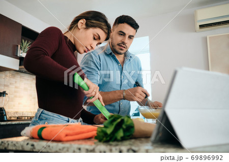 Couple Cooking Together Watching Tutorial For Recipe 69896992