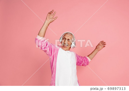 Senior hipster man in stylish pink attire isolated on pink background. Tech and joyful elderly lifestyle concept 69897313