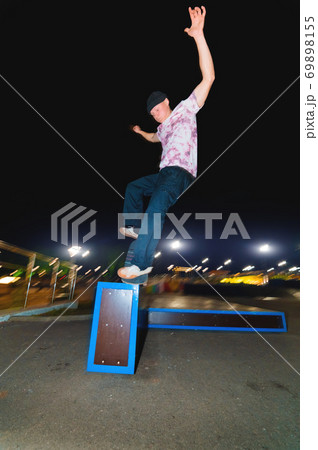 Young skater doing trick slide on railing in skatepark at night Young skater doing trick slide on railing in skatepark at night 69898155