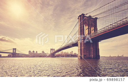 Vintage toned picture of Brooklyn Bridge against the sun, New York. 69898157