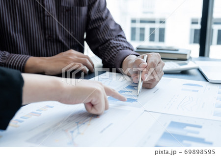 Two business leaders discussing the charts and graphs showing the results, Planning to start a new strategy for big success In the office Two business leaders discussing the charts and graphs showing the results, Planning to start a new strategy for big success In the office 69898595