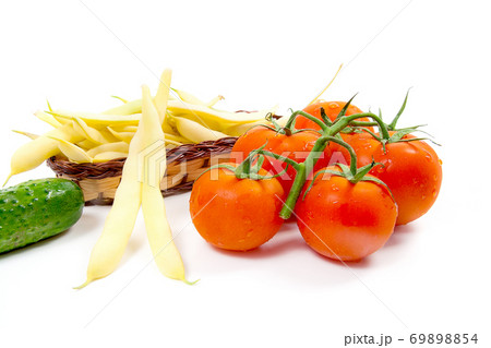 Fresh young pods of beans with beans, bunch of the fresh red tomatoes and several green cucumber with water drops on white background.. Fresh young pods of beans with beans, bunch of the fresh red tomatoes and several green cucumber with water drops on white background.. 69898854