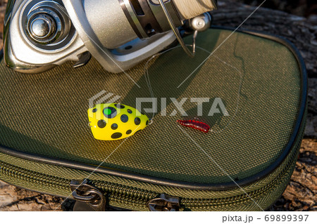 Fishing reel and various kind of baits on the natural background. 69899397