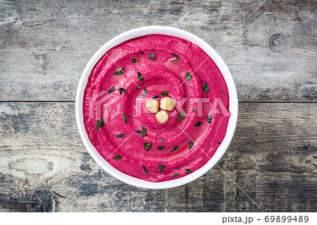 Beet hummus in a bowl on wooden table. Top view. Beet hummus in a bowl on wooden table. Top view. 69899489