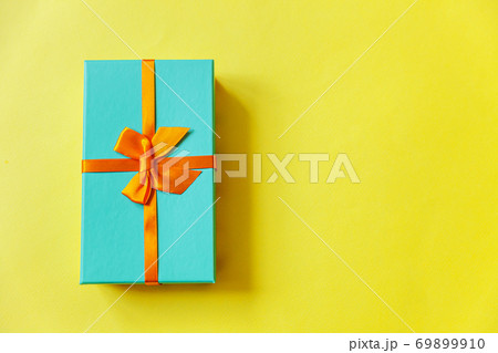 Christmas New Year birthday valentine celebration present romantic concept. Simply minimal design blue gift box isolated on yellow colorful background. Flat lay top view copy space. 69899910