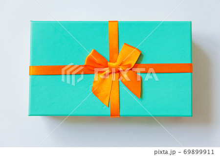Christmas New Year birthday valentine celebration present romantic concept. Simply minimal design blue gift box with orange ribbon isolated on white background. Flat lay top view copy space. 69899911