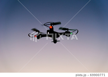 Toy drone quad copter against sunset sky Toy drone quad copter against sunset sky 69900771