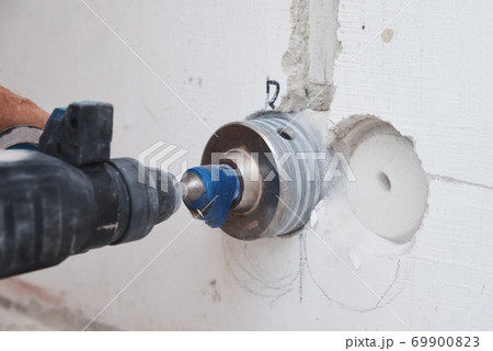 Builder with hummer drill perforator drills hole in a wall 69900823
