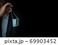 The man takes a disposable medical mask out of his pocket instead of a napkin. A man with a disposable mask in a suit. Respiratory protection. 69903452