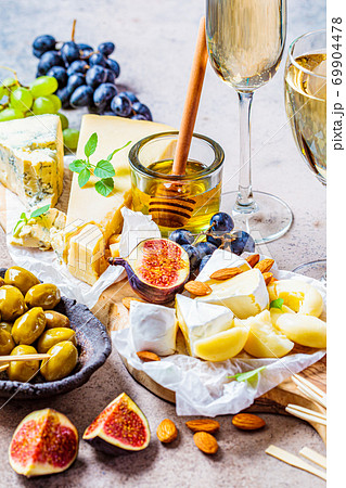 Cheese plate served with fruits, honey and snacks, close up. Assorted cheese background. Cheese plate served with fruits, honey and snacks, close up. Assorted cheese background. 69904478