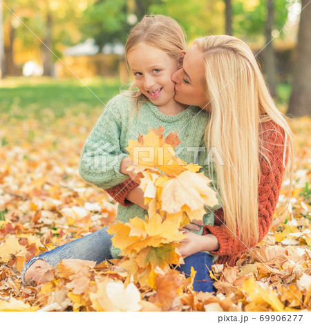 Woman and girl holding autumn yellow leaves Woman and girl holding autumn yellow leaves 69906277