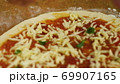 Cooking pizza. Chef put cheese and basil on the base of the pizza greased with tomato paste. A man 69907165