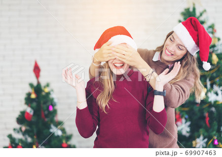 Happy women couple wearing Santa costume smiling and laughing with hand on face covering eyes 69907463