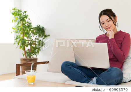 ソファーにあぐらでパソコンを操作する女性 69908570