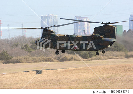 粉塵にまみれて離陸する自衛隊ヘリコプターの写真素材