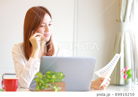 笑みを浮かべて電話するビジネスウーマン 69910250