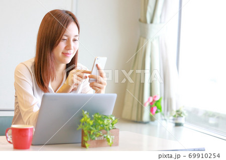 含み笑いでスマホを操作する女性 69910254