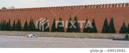 Red Square at spring overcast day. Red brick Kremlin wall, spruce trees. Stone pavement. Coronavirus pandemic time. No people. Single police car only. 69910681