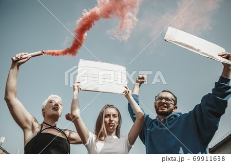Group of activists giving slogans in a rally. Men and women marching together in a protest in the city. 69911638
