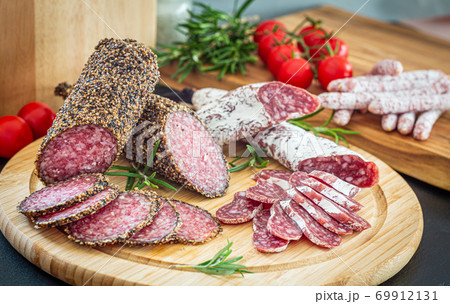 Assorted sliced italian salami on wooden plate Assorted sliced italian salami on wooden plate 69912131