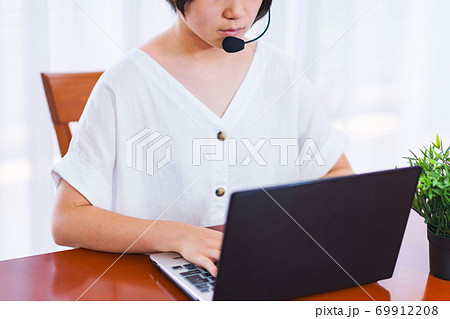 オンラインミーティングをインカムつけて自宅リビングで行う【テレワークのイメージ】 69912208
