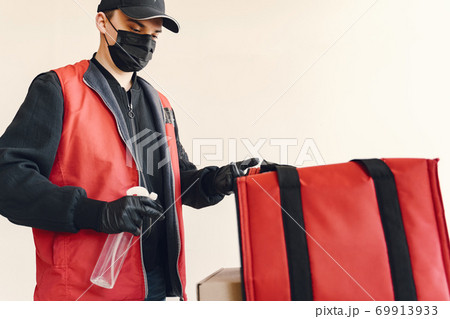 Delivery man spray sanitizing on a box Delivery man spray sanitizing on a box 69913933