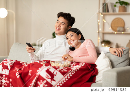 Happy Chinese Couple Watching TV On Christmas Eve At Home 69914385