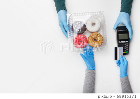 Sweets and cake set and modern payment. Client picks up container of donuts with bright glaze and pay by credit card at terminal 69915371