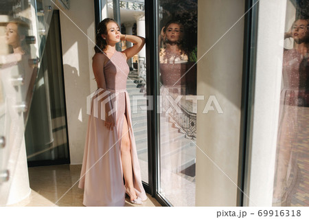 Elegant young woman stand by big window in luxury restaurant Elegant young woman stand by big window in luxury restaurant 69916318