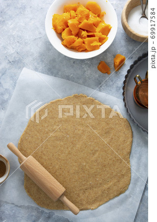 Rolled out dough for pie, or tart crust with pumpkin, squash. Cooking autumn dessert. 69917584
