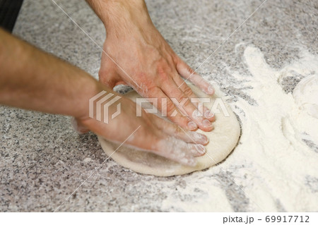 Making dough by male hands on table background. 69917712