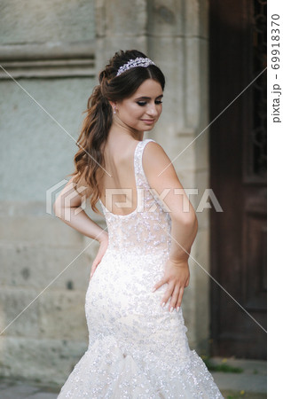 Elegant model in wedding dress posing to photographer outdoors. Beautiful young woman with fashion makeup Elegant model in wedding dress posing to photographer outdoors. Beautiful young woman with fashion makeup 69918370