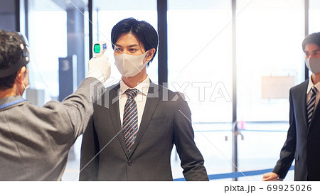 非接触温度計で体温測定を受ける男性 69925026