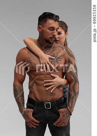 Woman hugging muscular man from behind 69925356