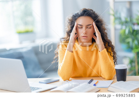 Young woman studying and having a head ache 69925885