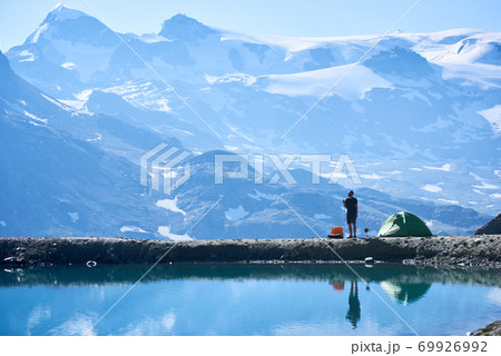 Man using radio near tent in mountains. Man using radio near tent in mountains. 69926992