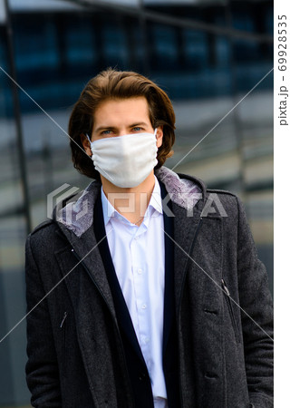 Young man in a medical mask outside, crisis, poverty, hardship. Quarantine, coronavirus, isolation. 69928535