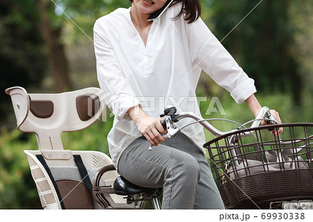 自転車に乗りながら通話する女性 69930338