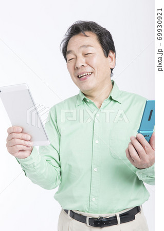 タブレットPCとガラケーを持つ男性 69930921