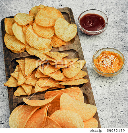 Chips, snacks and crackers on a wooden board. Fast food. Chips, snacks and crackers on a wooden board. Fast food. 69932159